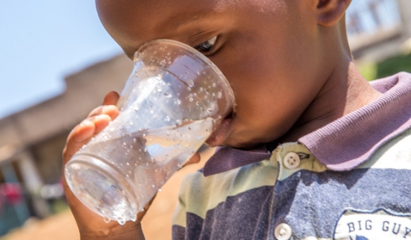 A kid drinking water from Maji Safi Kiosk- Sondu